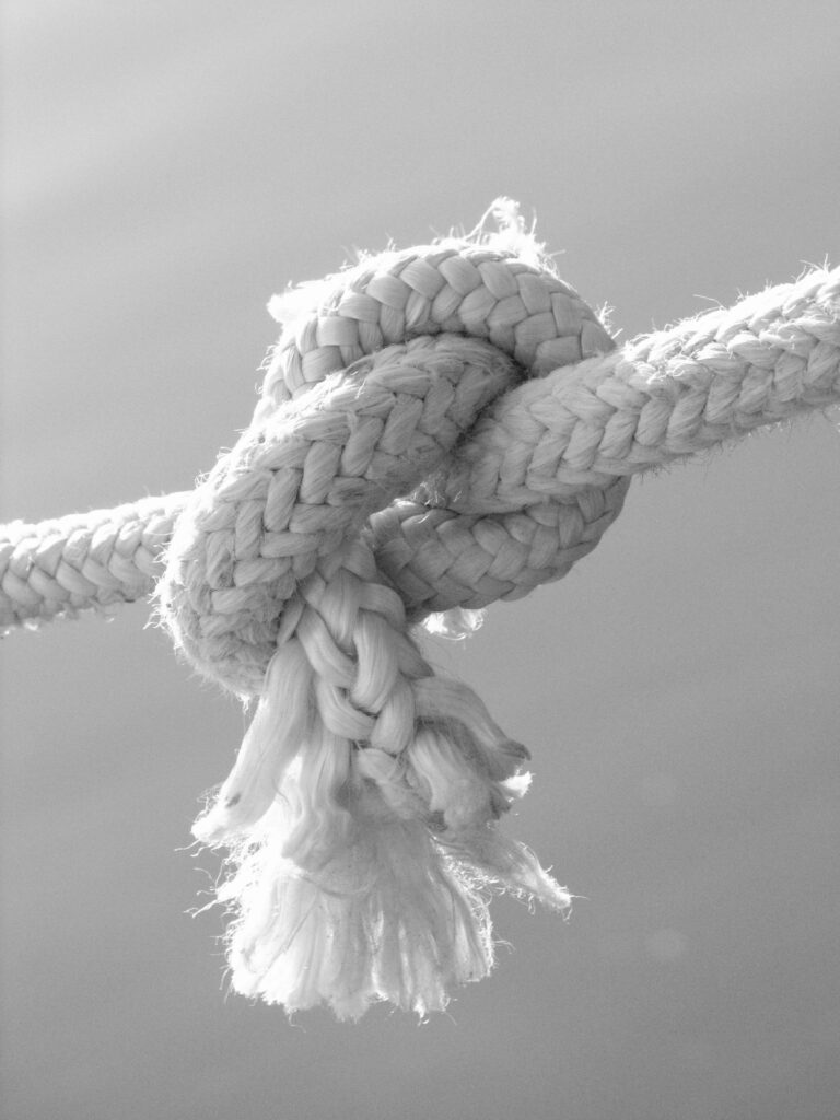 A detailed black and white close-up of a tied rope knot, emphasizing texture.